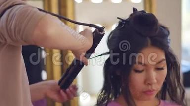 专业的发型师，发型师，梳着一个美丽模特的头发，有着亚洲的外表。 美容美发护理